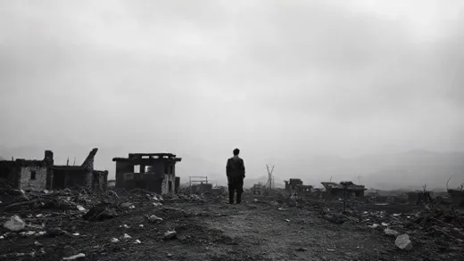 A poignant black and white photo of a devastated Korean landscape after the war, showing ruined buildings and a solitary figure looking towards the horizon. The atmosphere is somber and reflective.