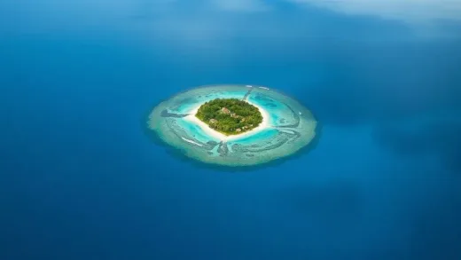 A captivating aerial view of a small, emerald-colored island in the vast blue Pacific Ocean. The island features lush greenery and visible coral reefs in shallow waters, with a hint of a small, peaceful village. Emphasize the beauty and mystery of the remote island.