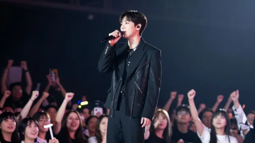 A charismatic male singer, Lim Young-woong, on stage, bathed in spotlights, with a diverse audience cheering. The image should convey a sense of a grand performance and widespread appeal. Focus on his versatile image, not just trot, showing him connecting with the audience.