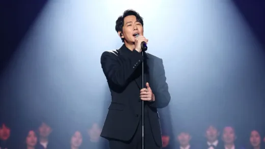 A majestic, dramatic image of a legendary male Korean trot singer on a brightly lit stage, performing with passion, surrounded by a faint, almost ethereal glow, suggesting a timeless and impactful presence. The audience is blurred in the background, focused on the singer.