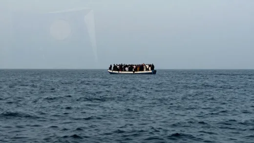 An impactful image of a vast sea with a small, overcrowded boat of refugees in the distance, juxtaposed with subtle hints of European cityscapes or flags, conveying a sense of urgent crisis and the vastness of the issue. The mood should be somber and thought-provoking.