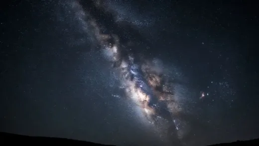 A breathtaking view of the Milky Way galaxy stretching across a starry night sky, with a silvery river of stars flowing through darkness, capturing the majestic beauty of our galaxy from Earth's perspective