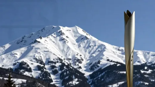 A captivating image of snow-capped mountains and a modern Olympic torch, with a subtle hint of historical elements in the background, drawing viewers into a story of sports and challenges. The mood is intriguing and thought-provoking.