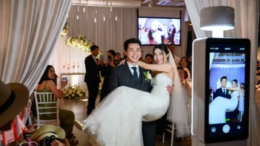 A modern wedding ceremony in 2026 with a photobooth and a couple performing a unique entrance, happy guests.