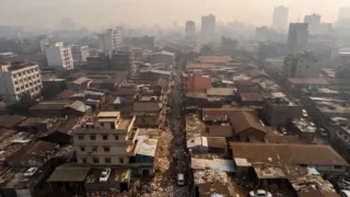 Aerial view of a densely populated and polluted city, Dhaka, Bangladesh, with visible smog and overflowing waste.