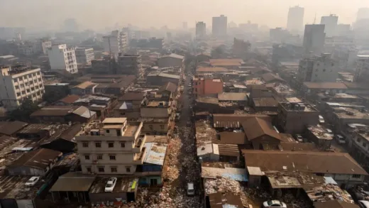 Aerial view of a densely populated and polluted city, Dhaka, Bangladesh, with visible smog and overflowing waste.