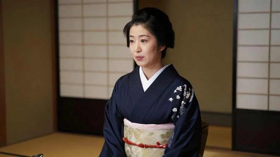 A sophisticated Japanese woman in traditional Kyoto kimono speaking elegantly with subtle facial expressions, in a historic Kyoto tea house setting with sliding doors and tatami mats, conveying dual meaning through polite gestures