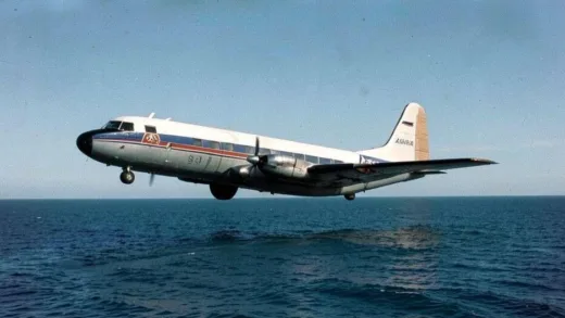 A vintage 1960s Korean Air Lines YS-11 aircraft flying over the East Sea under a clear sky, viewed from a slightly high angle, conveying a sense of historical mystery and the beginning of a journey.