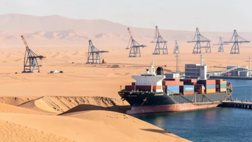 A vast desert landscape with oil rigs in the distance, juxtaposed with a container ship unloading goods at a modern port, symbolizing unexpected imports.