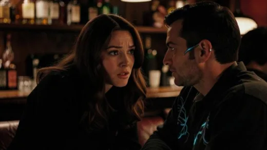 A woman with a captivated expression, leaning slightly towards a man with a subtle, non-threatening alien-like feature (e.g., a faint glow on his hand or a unique pattern on his clothes) in a cozy, dimly lit bar. The atmosphere is mysterious and alluring.