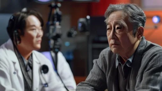 A famous middle-aged Korean comedian sitting in a YouTube studio with a neurologist doctor. The comedian looks serious and contemplative. Modern broadcasting equipment visible. Warm studio lighting. Documentary style.