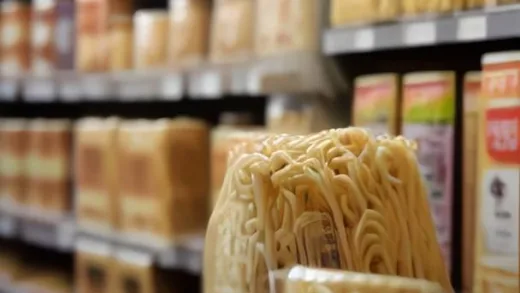 A package of gourmet ramen noodles on a store shelf, looking premium but with a price tag that stands out, symbolizing its high cost and market challenges. The background is slightly blurred supermarket aisle.