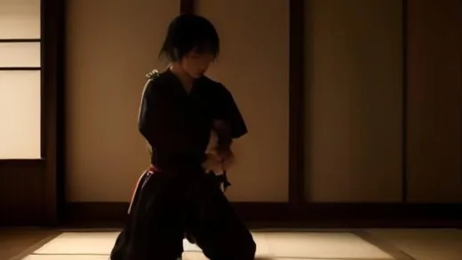 A solemn samurai in traditional attire, kneeling before a short sword, ready to perform seppuku, with a sense of honor and determination on his face. The setting is a dimly lit, traditional Japanese room with subtle light filtering in.