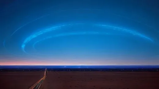 A vast, arid Texas landscape under a dramatic sky, with a futuristic data center glowing with blue light, connected by intricate power lines.